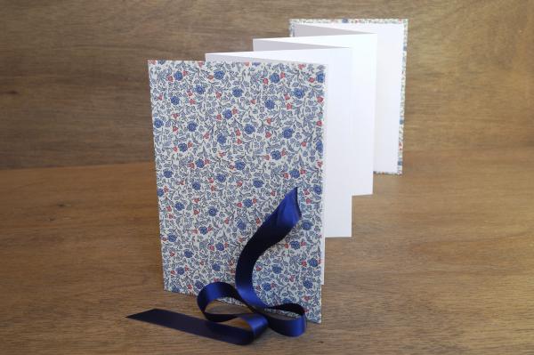 Leporello open, accordion, light photo cardboard, cover with decorative paper and blue flowers, blue satin bow